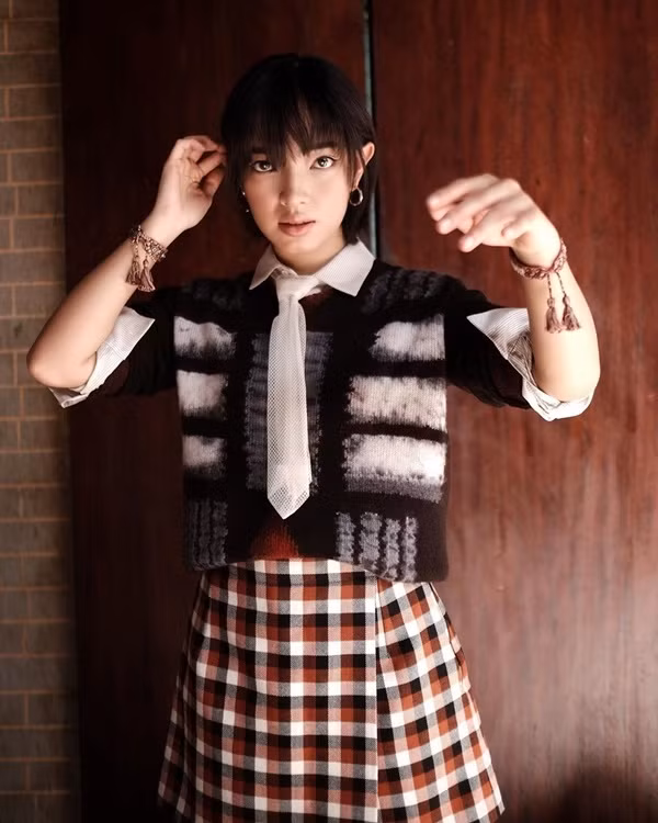 Châu Bùi mang đến set đồ đầy thú vị khi mix layer sơ mi trắng cùng áo len và chân váy kẻ caro.