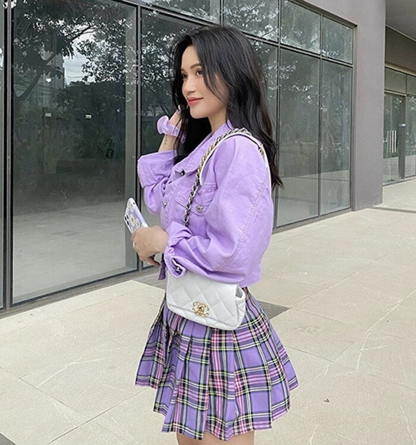 Sĩ Thanh lại chọn diện đồ &quot;ăn gian&quot; tuổi với cả cây tím lịm tìm sim. Cô nàng mix đồ theo phong cách high teen cổ điển với jacket dáng ngắn, chân váy kẻ caro xếp ly và túi xách đồng điệu.