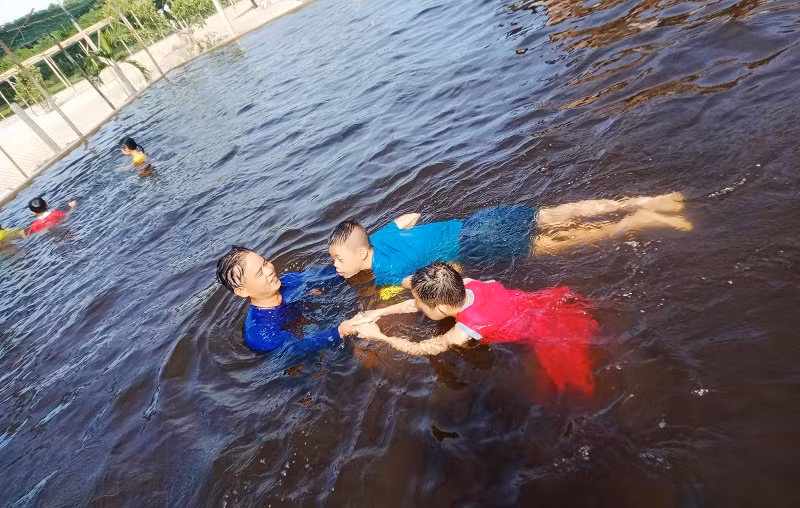 Thầy Tước hướng dẫn cho 2 em khuyết tật các động tác khi bơi.