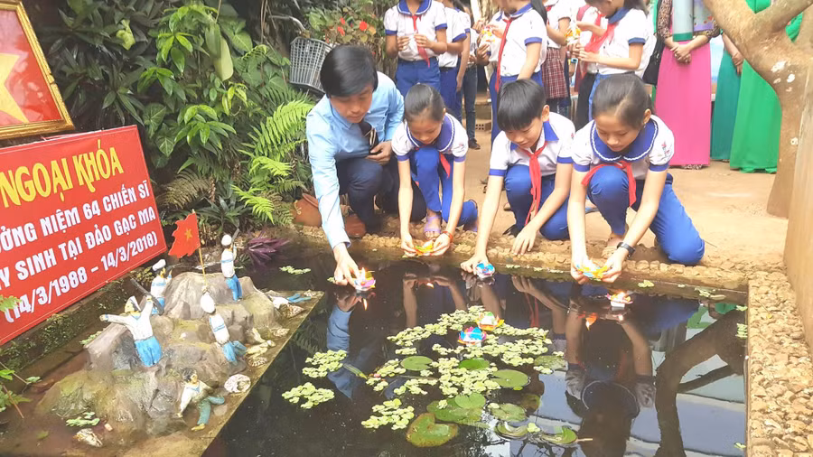 Thầy Trọng và học sinh Trường Tiểu học Hướng Phùng bên mô hình đảo Gạc Ma.