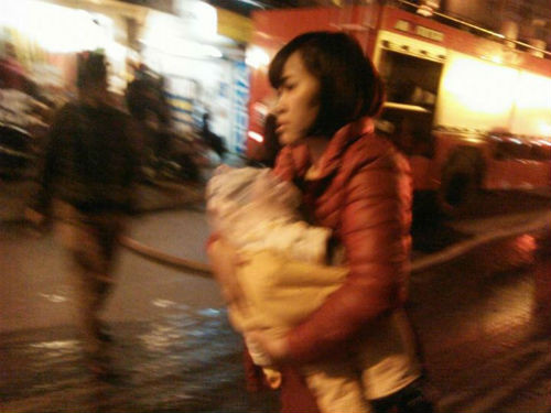 Một người phụ nữ bế con chạy khỏi đám cháy.