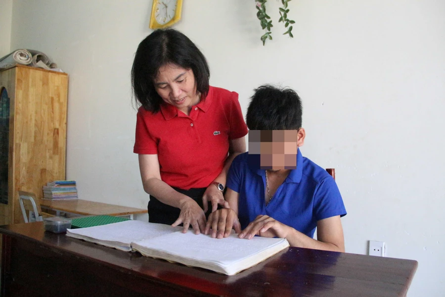 Cô Lương Thị Hồng Phượng hướng dẫn Quốc Khánh đọc chữ Braille (chữ viết dành cho người khiếm thị).