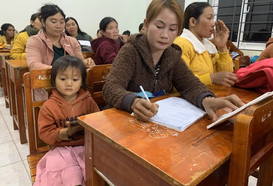 Một em bé theo mẹ đến lớp “bình dân học vụ”. Ảnh: TT