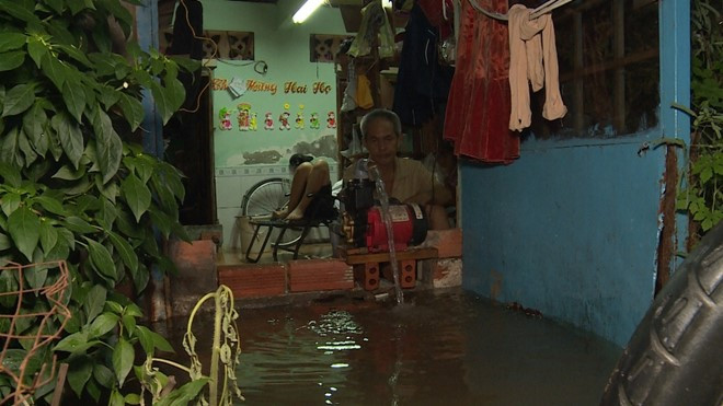 Gia đình ông Nguyễn Vọng Cát dùng máy bơm bơm nước ra khỏi nhà.