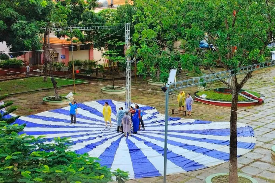 Giáo viên Trường THCS Bình Khánh (TP Long Xuyên, An Giang) đội mưa chuẩn bị sân lễ.