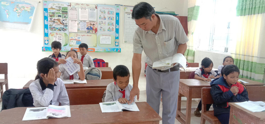 Thầy Ksơr Y Chét hướng dẫn học sinh đọc bài. Ảnh: NTCC Thầy Ksơr Y Chét hướng dẫn học sinh đọc bài. Ảnh: NTCC