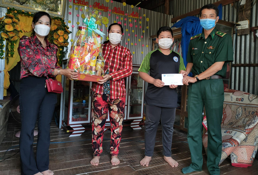 Cán bộ Đồn Biên phòng Phú Hữu cùng chính quyền địa phương tặng quà cho con nuôi của đơn vị.