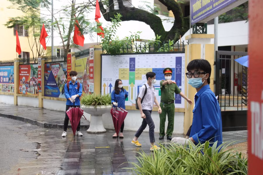 Công an phân làn thí sinh đi 2 cổng để bảo đảm giãn cách tại điểm thi Trường THPT Trần Nhân Tông sáng 13/6.