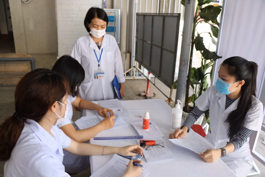 Các nhân viên y tế hướng dẫn mọi người làm thủ tục....