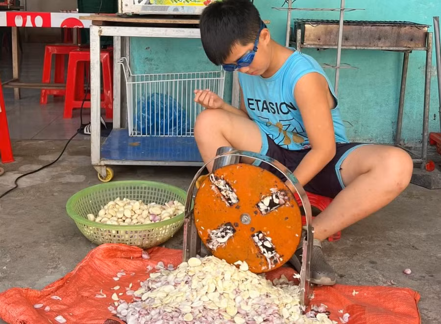 Con trai chị Võ Thị Ngọc ở thị xã Cửa Lò (Nghệ An) giúp mẹ thái tỏi. Ảnh: NVCC