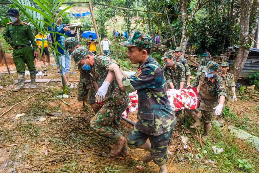 Lực lượng chức năng đang khiêng thi thể một nạn nhân vừa được tìm thấy.