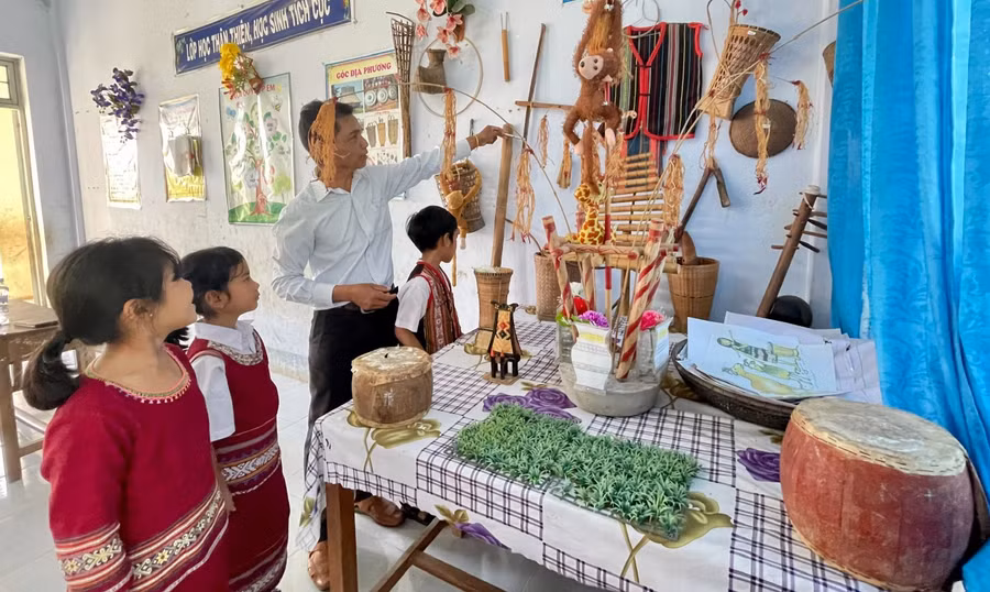 Thầy A Dưnh dạy học sinh tiếng Jrai thông qua đồ dùng, nhạc cụ truyền thống của dân tộc. Ảnh: Trúc Hân