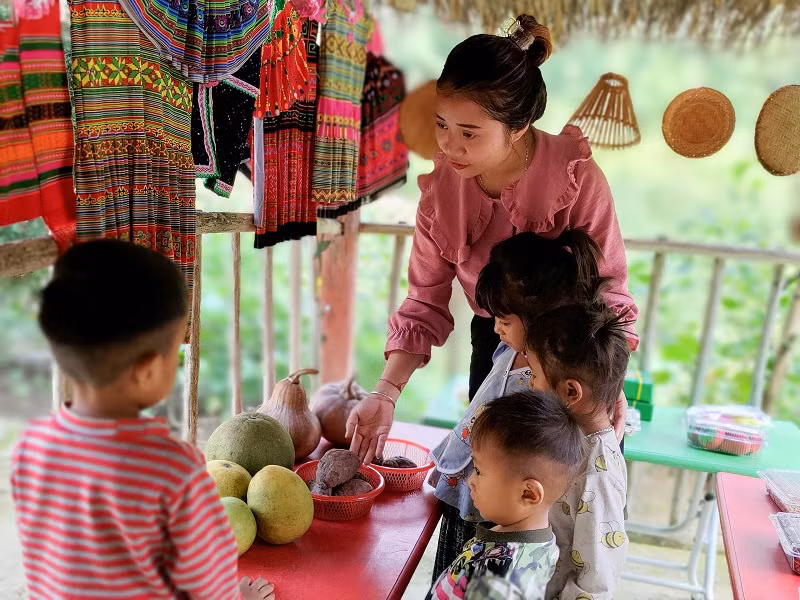 Cô Mè Thị Nhất “thổi hồn” cho khu trải nghiệm “Góc chợ quê” bằng những đồ thổ cẩm mà cô dùng tiền lương để mua và các loại củ quả do bà con trong bản tự trồng cấy.