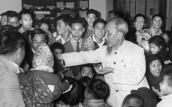 Bác Hồ phát kẹo cho con em những người làm Báo Nhân Dân tại trụ sở 71 Hàng Trống (nghệ sĩ Trịnh Hải đeo cà-vạt đứng cạnh Bác). Ảnh: Nguyễn Kim Côn