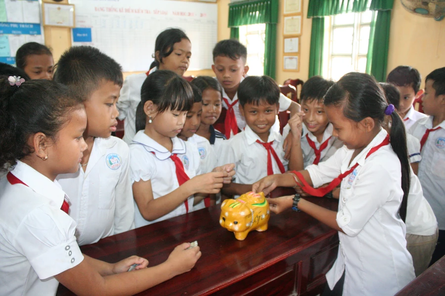 Học sinh Trường Tiểu học Hàm Giang B cùng nhau nuôi heo đất giúp bạn dịp Tết. Ảnh: Q. Ngữ