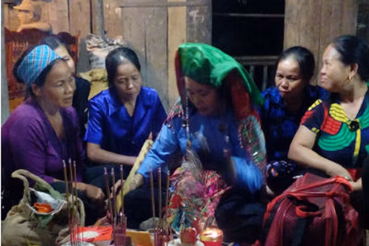 Thầy Pựt Lưu Thị My đang ngồi trước mâm cúng làm đám giỗ cho một gia đình ở xã Quang Hán (Trà Lĩnh, Cao Bằng)