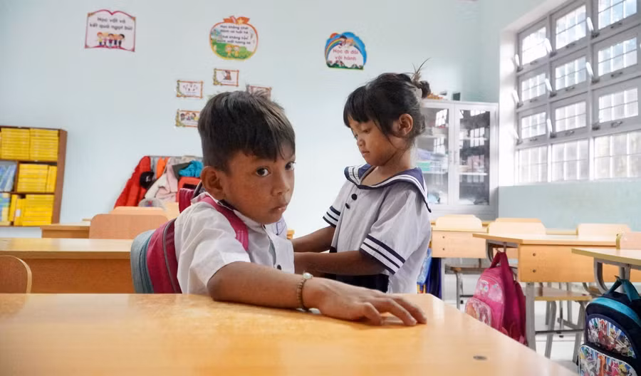 Y Juyên giúp cậu bạn A Đinh cất cặp sách khi đến lớp. Ảnh: Dung Nguyễn