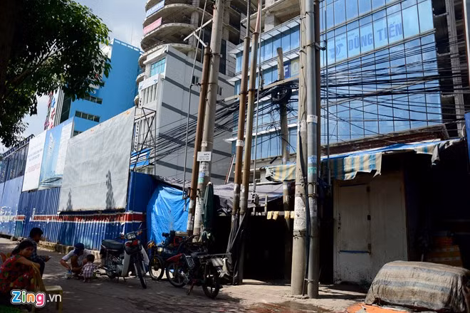 Phía trước dự án hiện là một điểm sửa xe, bán đá lạnh, cột điện dày đặc, dây chằng chịt. Những cao ốc dở dang, bị bỏ hoang ở Sài Gòn