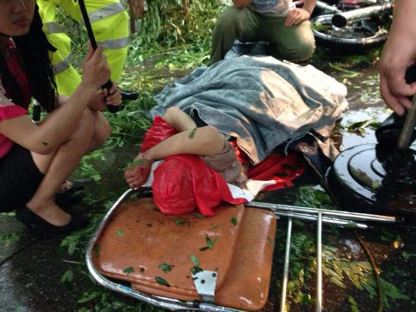 Mọi người che ô cho nạn nhân trong lúc chờ xe cấp cứu.