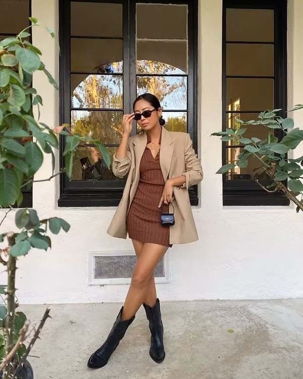 Aimee Song lại sử dụng những tông màu trung tính để tạo nên cho mình set đồ thu đơn giản mà vô cùng thời thượng. Blogger thời trang xứ Hàn diện váy liền dáng ôm màu nâu mix cùng blazer phủ tông be, khéo kết hợp thêm phụ kiện ton sur ton đen như boots da, túi xách mini và kính mắt.