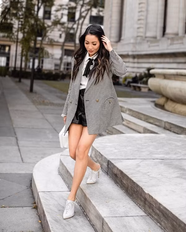 Cũng lên đồ với blazer xuống phố trong một ngày đẹp trời mùa thu nhưng Wendy Nguyễn lại chọn cho mình bộ cánh trẻ trung, thanh lịch nhưng không kém phần năng động. Qúy cô thời trang gốc Việt diện sơ mi trắng với blazer họa tiết và quần short da, hoàn thiện set đồ bằng đôi boots hở gót sang chảnh.