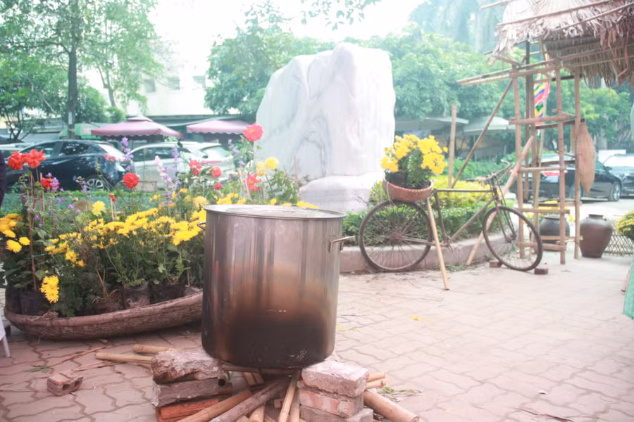 Tiểu cảnh thể hiện không khí Tết ấm áp với nồi luộc bánh Chưng xanh và hoa cúc vàng tươi