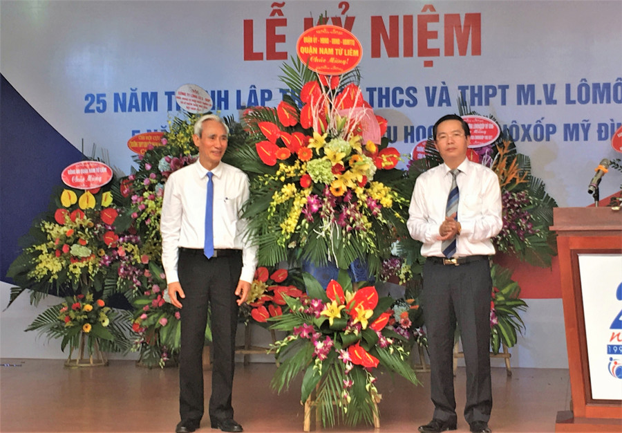 NGƯT Nguyễn Phú Cường (trái) đại diện Hệ thống giáo dục Lômônôxốp - nhận hoa chúc mừng từ ông Trần Thanh Long - Phó Chủ tịch UBND quận Nam Từ Liêm