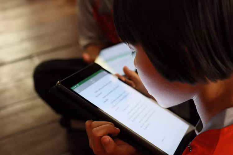 Một HS nghèo đọc sách từ ứng dụng của dự án Learning Coin.