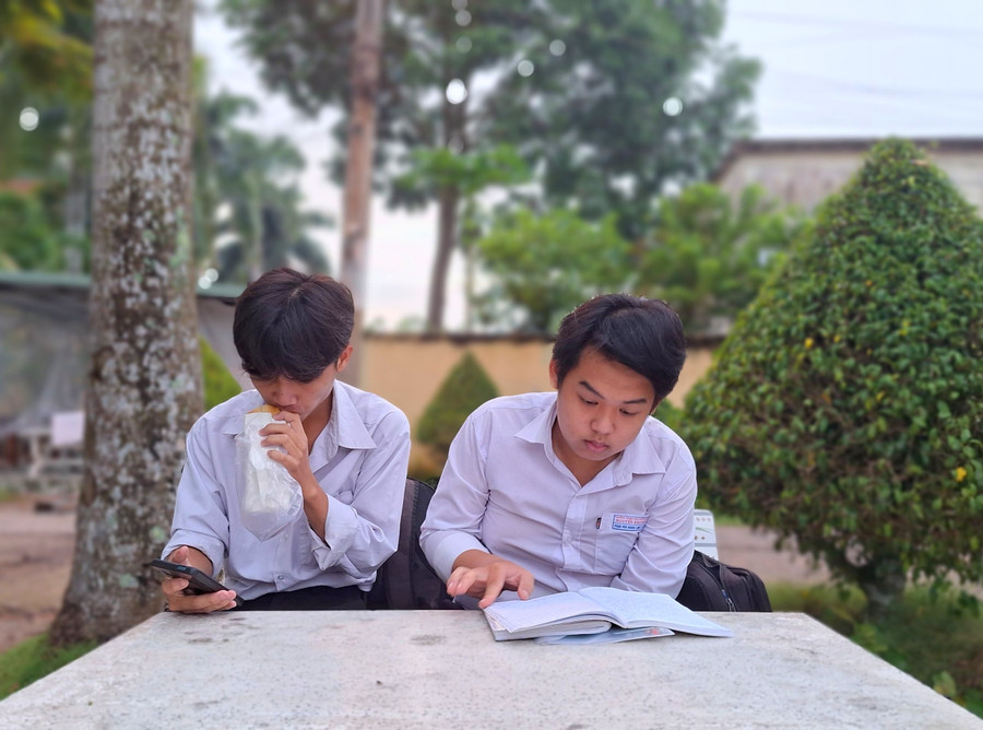 Thí sinh vừa tranh thủ ăn sáng vừa xem lại bài trước giờ thi.