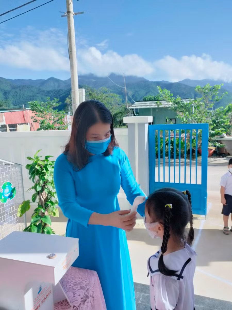 Học sinh Lớp Một, Trường Tiểu học Hòa Bắc đo thân nhiệt trước khi vào lớp ở buổi học trực tiếp đầu tiên
