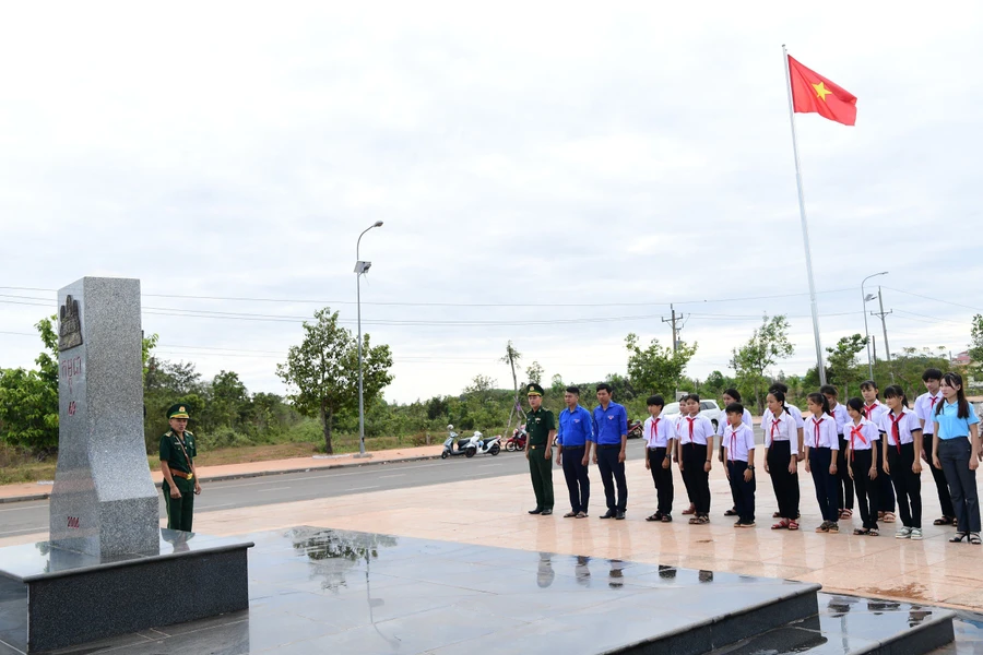 Học sinh nghe cán bộ Đồn Biên phòng cửa khẩu quốc tế Hoa Lư giới thiệu về ý nghĩa, lịch sử và cấu tạo của cột mốc. Ảnh: Hồng Ánh