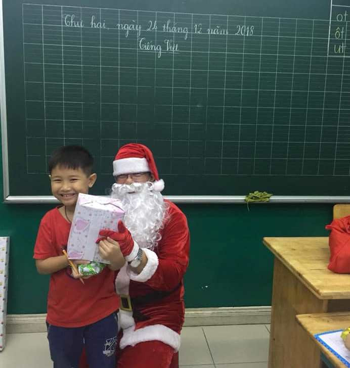Một bạn học sinh vui vẻ nhận quà và bất ngờ khi thầy giáo đóng vai ông già Noel