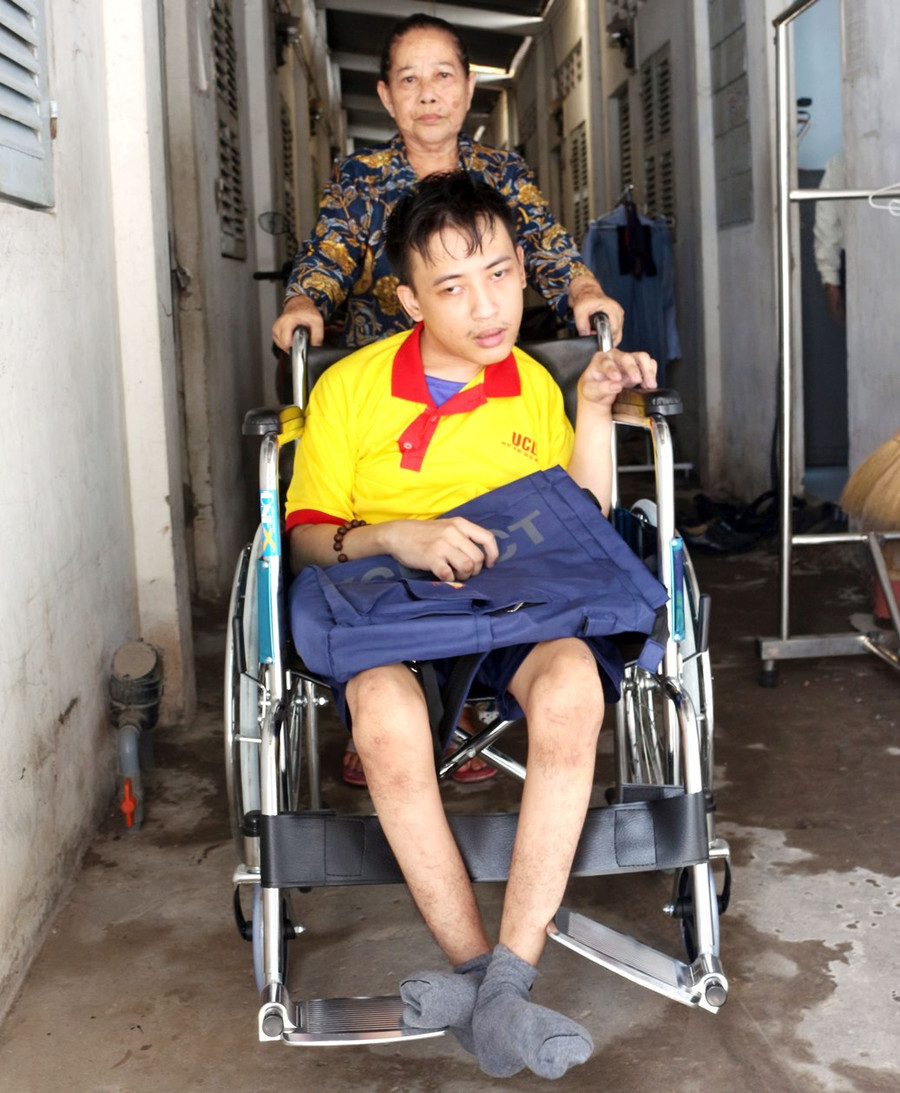 Bà Phụng đẩy xe lăn đưa cháu đến trường.