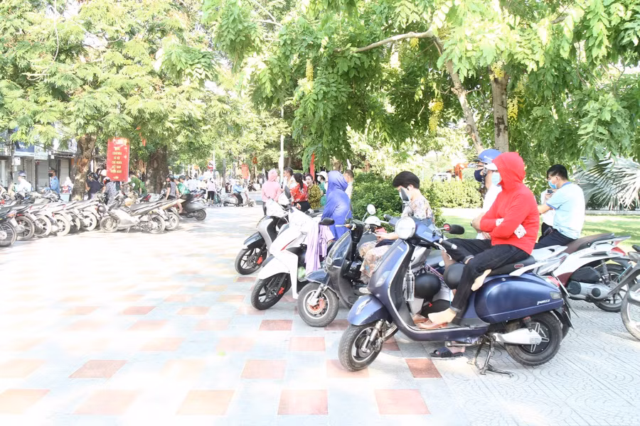 Phụ huynh chờ con trên vỉa hè công viên, thực hiện nghiêm phòng chống dịch Covid-19.