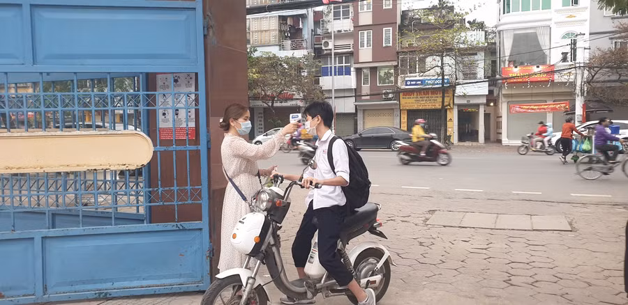 GV Trường THCS Nguyễn Bá Ngọc đo thân nhiệt cho học sinh ngay từ cổng trường