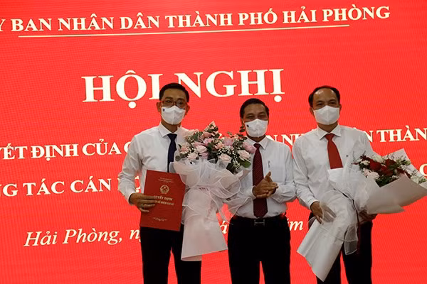 Ông Nguyễn Văn Tùng- Chủ tịch UBND TP (giữa) trao quyết định bổ nhiệm cho tân Giám đốc Sở GD&amp;ĐT Hải Phòng Bùi Văn Kiệm (bìa trái) và tặng hoa chúc mừng ông Lê Quốc Tiến nhận nhiệm vụ mới
