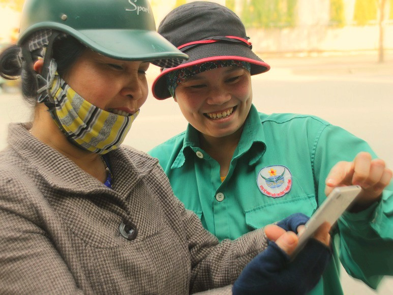 Chị Thơm (phải) được đồng nghiệp cho xem những bức ảnh của mình tràn ngập trên mạng xã hội. Ảnh: Ngọc Tân.