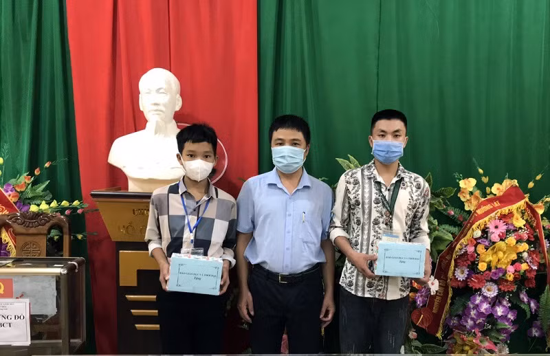 Thầy Trần Anh Văn – Hiệu trưởng Trường THPT Mường Lát trao điện thoại cho em Thao Văn Chá (trái) và em Đinh Công Tú.