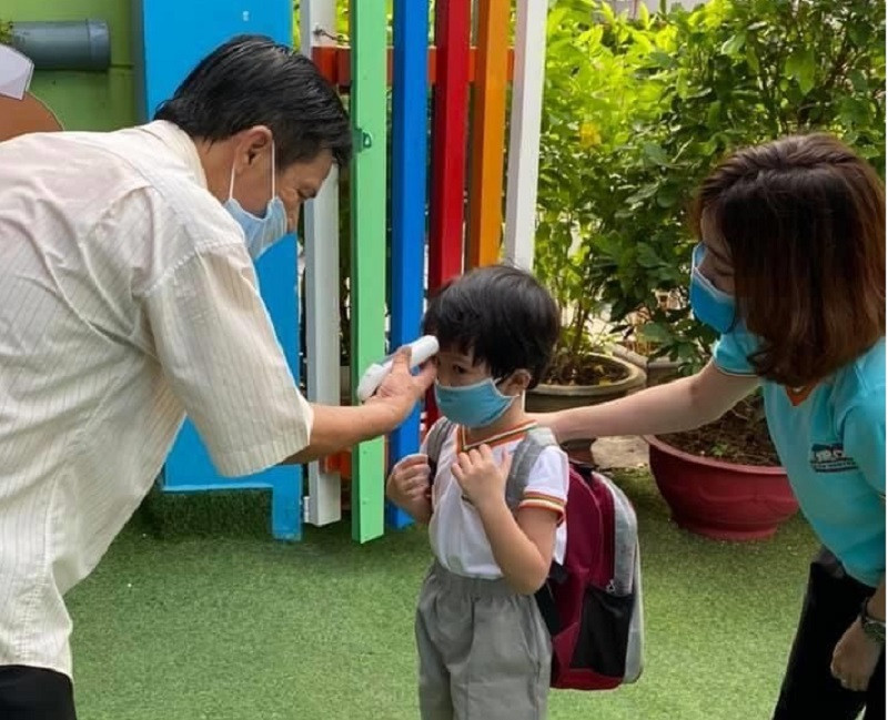 Học sinh mầm non TPHCM đến trường được đo thân nhiệt, đeo khẩu trang để phòng dịch Covid-19 năm 2020. Ảnh: NTCC