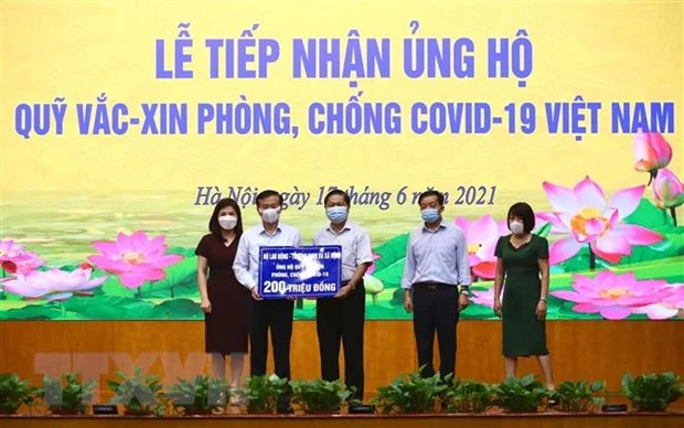 Thứ trưởng Bộ Lao động, Thương binh và Xã hội Lê Tấn Dũng (giữa) trao ủng hộ Quỹ cho Phó Tổng giám đốc Kho bạc Nhà nước Nguyễn Quang Vinh. (Ảnh: Hoàng Hiếu/TTXVN).