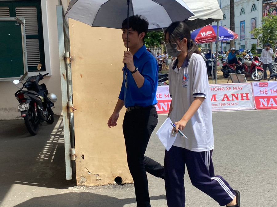 Tình nguyện viên che ô đón thí sinh vào trường thi. Tình nguyện viên che ô đón thí sinh vào trường thi.