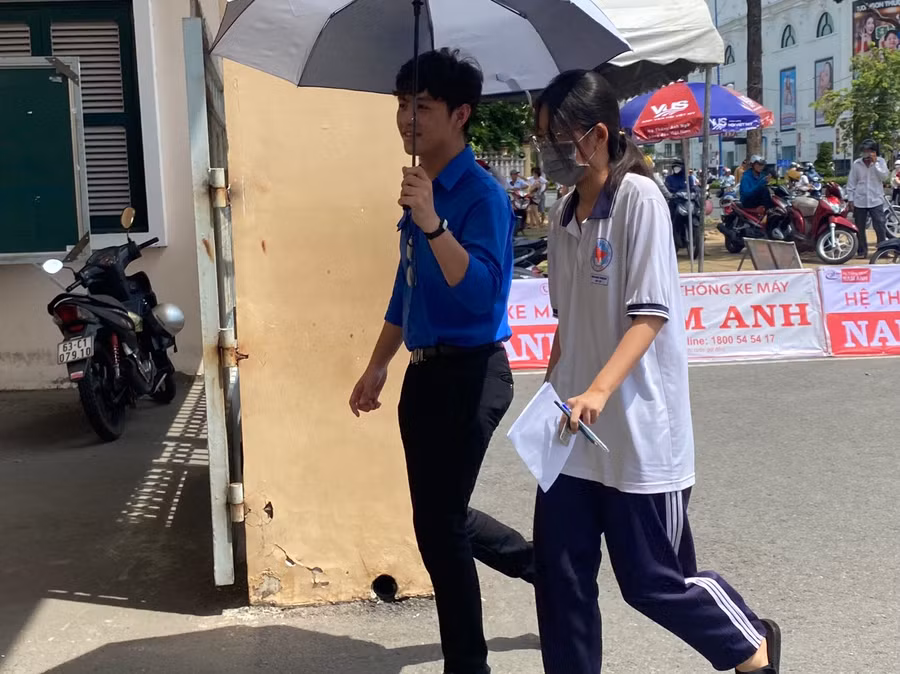 Tình nguyện viên che ô đón thí sinh vào trường thi.