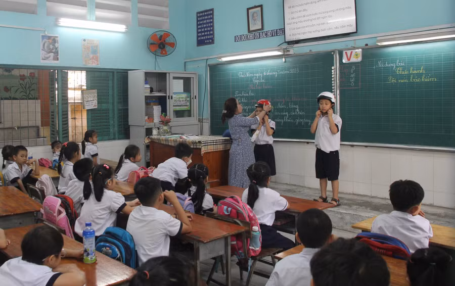 Giáo viên Trường Tiểu học Hà Huy Giáp (Quận 12) hướng dẫn học sinh đội mũ bảo hiểm đúng cách. Ảnh: Minh Anh