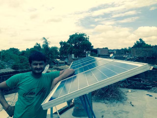 Chủ cửa hàng nạp điện cho đèn bằng tấm năng lượng mặt trời trên mái nhà.