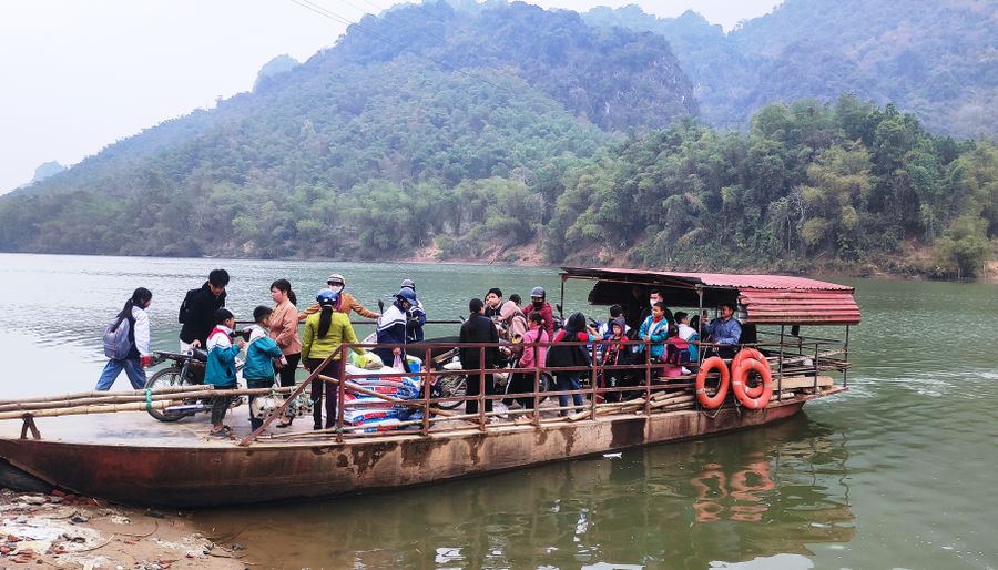 Học sinh và người dân làng Bèo Bọt qua sông Mã trên chiếc đò ngang.