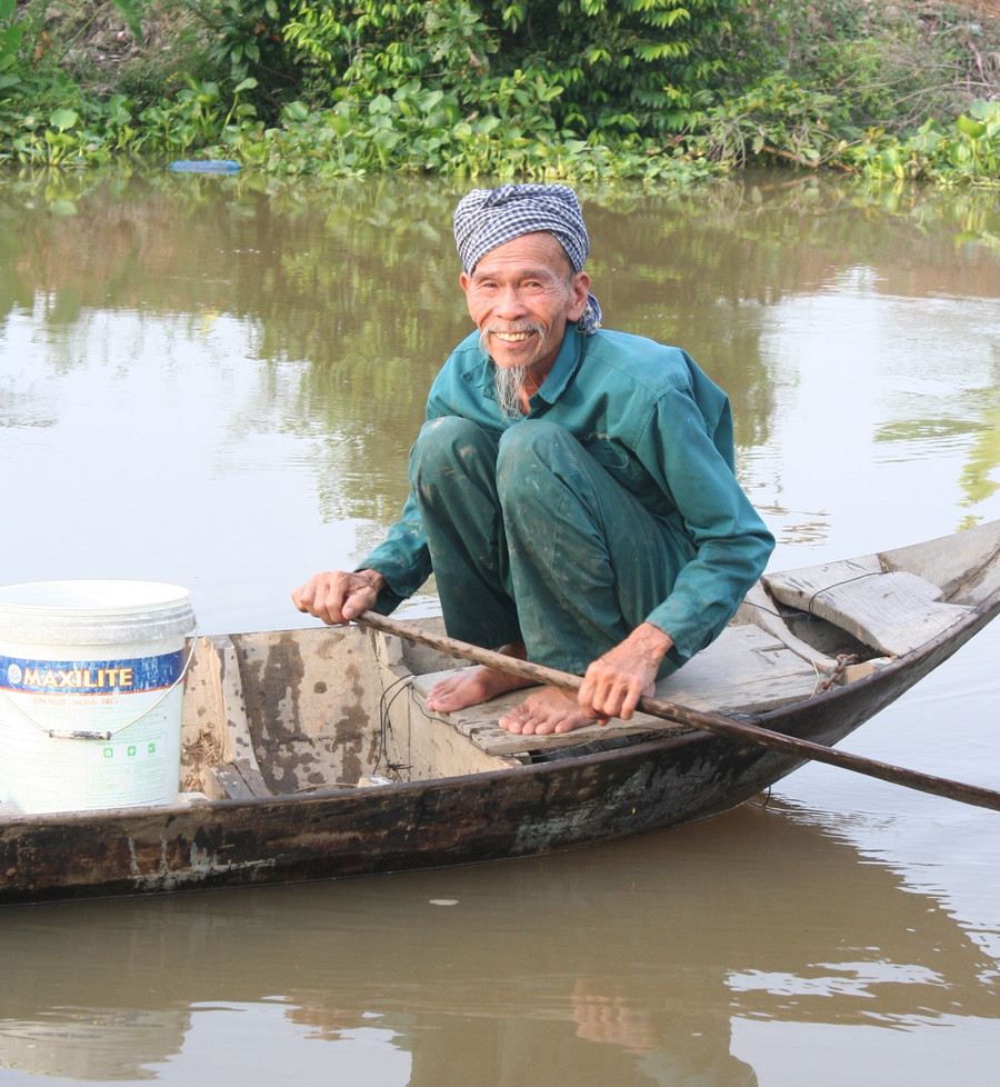 Ông Bảy bơi xuồng đi thăm dớn (dụng cụ bắt cá) ở con kênh trước nhà.