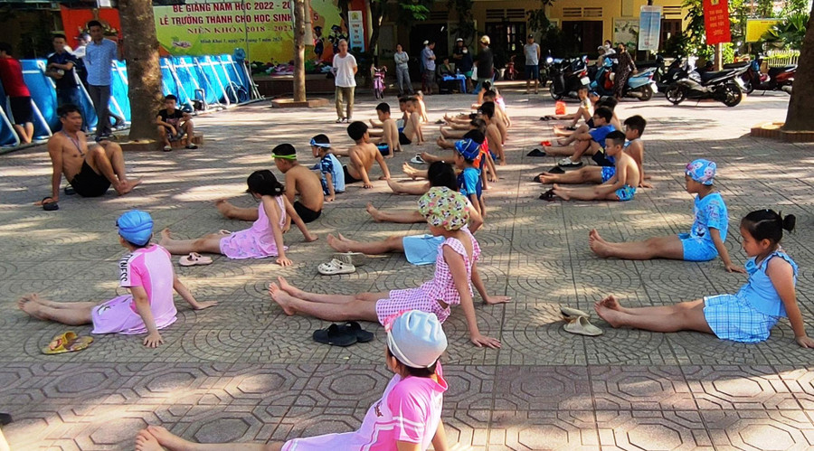 Học sinh được thầy giáo hướng dẫn cách khởi động trước khi xuống bể tập bơi. Học sinh được thầy giáo hướng dẫn cách khởi động trước khi xuống bể tập bơi.