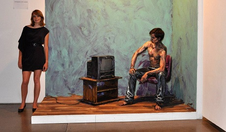 Tại một triển lãm, Alexa đang đứng cạnh bối cảnh sắp đặt trực quan để người xem có thể hiểu hơn về phong cách tạo hình thị giác của cô.