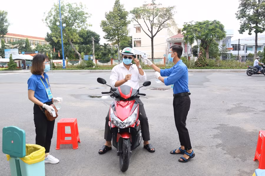 Cán bộ làm công tác thi tại Tiền Giang được đo nhiệt độ, khử khuẩn tay, thay khẩu trang trước khi vào điểm thi. Ảnh: X. Uyên.