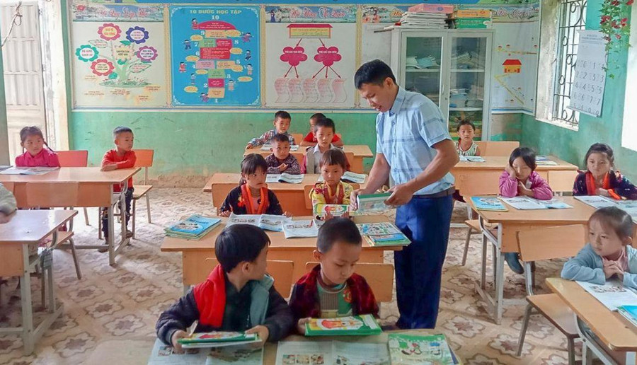 Thầy Lò Văn Thoàn phát sách mới cho học sinh trong buổi đầu tựu trường.